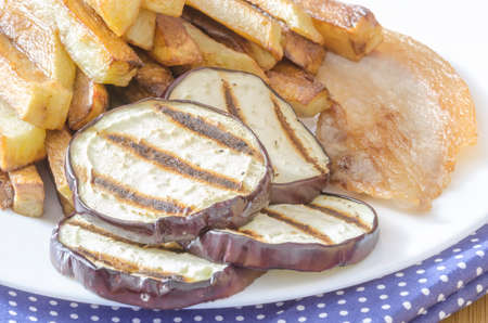 Fries potatoes with grilled eggplant on wooden backgroundの写真素材