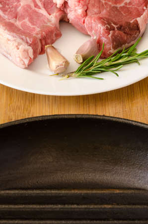 Raw steak with rosemary and garlic near cast-iron frying panの写真素材