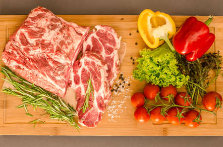 Raw meat with vegetables and spices on wooden backgroundの写真素材