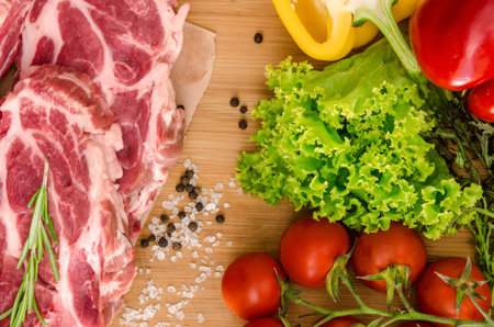 Raw meat with vegetables and spices on wooden backgroundの写真素材