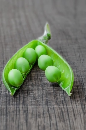Green organic peas on wooden background, shalow focusの写真素材