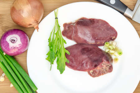 Raw chicken liver with vegetables on wooden backgroundの写真素材