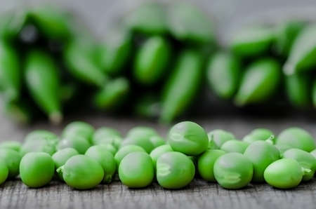 Green organic peas on wooden background, shalow focusの写真素材