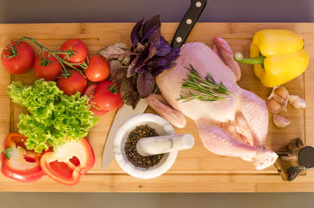 Raw chicken with vegetables and spice on wooden tableの写真素材