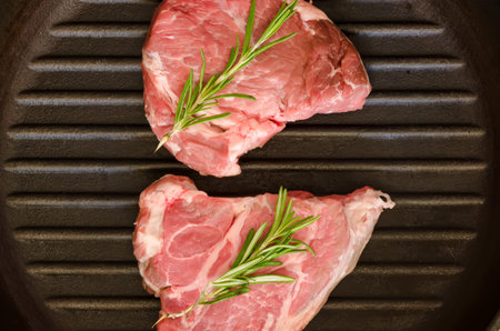 Raw steak with rosemary on cast-iron frying pan