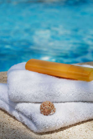 Holiday - Towels and sun lotion by swimming poolの写真素材