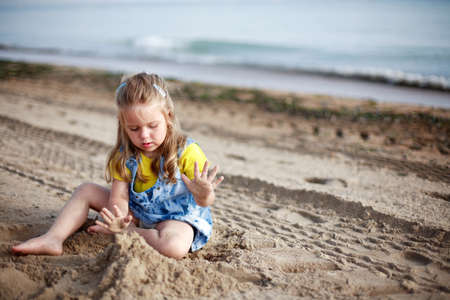 Cute kid playing with sand on a beachの写真素材