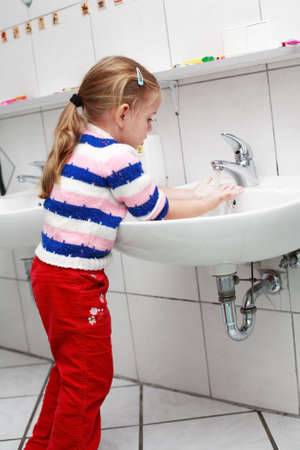 Small girl washing her hands in the bathroomの写真素材