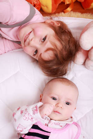 Cute older sister with small baby and toysの写真素材