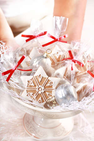 Woman hands giving bowl with small gingerbread gifts for guests on the tableの写真素材