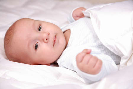 Portrait of adorable baby lying in bedの写真素材