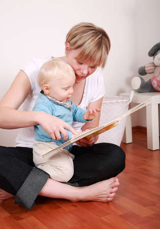 Cute little boy looking at picture book with his momの写真素材