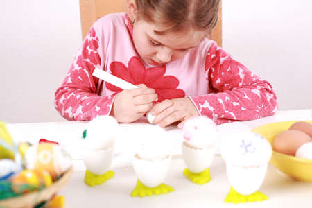 Cute little girl painting Easter eggsの写真素材