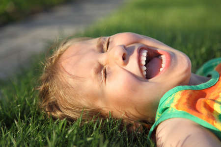 Happy cute girl laughing on a grass fieldの写真素材