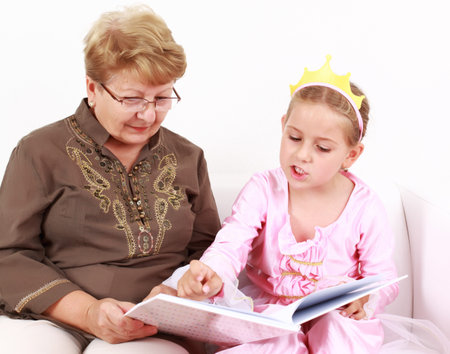 Cute little girl reading a book with her grandmother