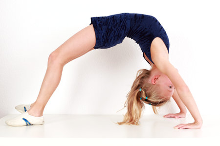 Girl child performing backward bend gymnastics on white backgroundの写真素材
