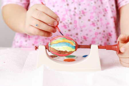 Cute little girl painting Easter eggsの写真素材