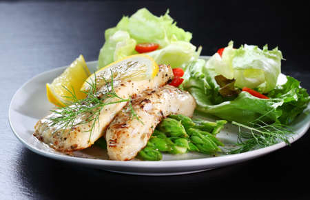 Delicious fried fish on green asparagus with saladの写真素材