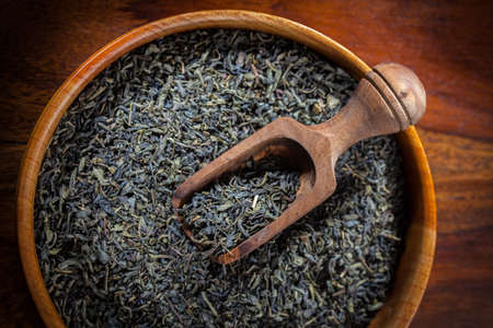 Dry green tea in a wooden bowlの写真素材