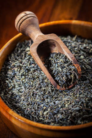 Dry green tea in a wooden bowlの写真素材