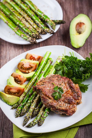 Glazed green asparagus with sesame seeds and grilled pork chopの写真素材
