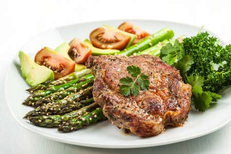 Glazed green asparagus with sesame seeds and grilled pork chopの写真素材