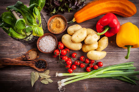 Raw vegetables with spices on wooden tableの写真素材