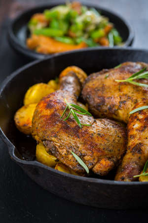 Baked chicken legs with potatos and vegetablesの写真素材