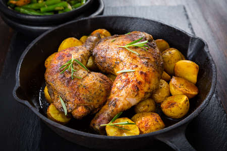 Baked chicken legs with potatos and vegetablesの写真素材