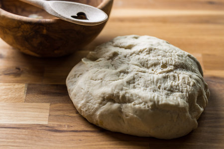 Fresh yeast dough for bread, pizza and baguettes on wooden background