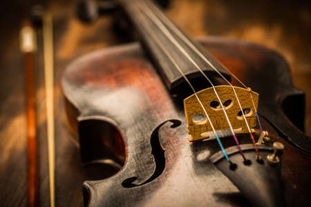Detail of old violin and bow in vintage style on wood backgroundの写真素材