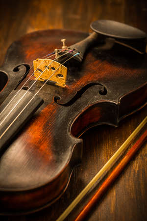 Detail of old violin and bow in vintage style on wood backgroundの写真素材