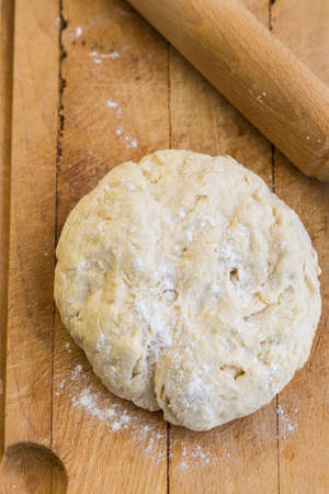 Fresh raw yeast dough with rolling pin on cutting boardの写真素材