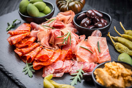 Platter of antipasti with a mixture of salami, prosciutto, chorizo, peppers, tomatoes and olivesの写真素材