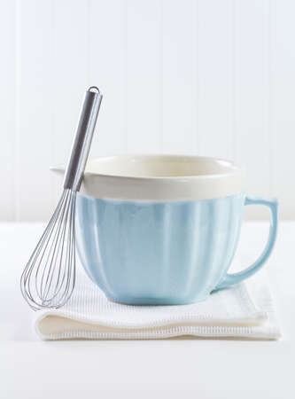 Blue mixing bowl with wisp for baking on white background. Kitchen utensil for cooking and baking.の写真素材