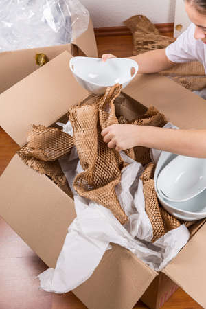 Detail of woman packaging fragile items using crumpled packing paper.の写真素材