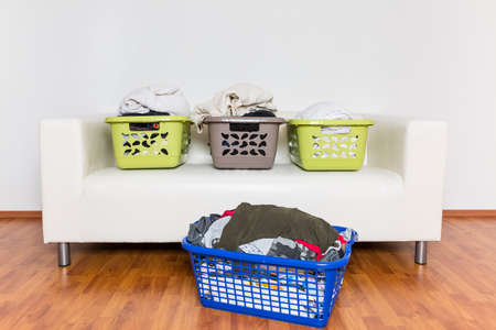 Overflowing laundry baskets full of dirty clothes on sofa.の写真素材