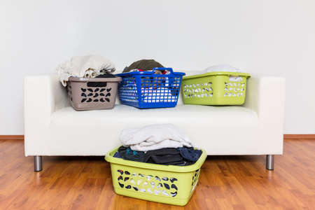 Overflowing laundry baskets full of dirty clothes on sofa.の写真素材