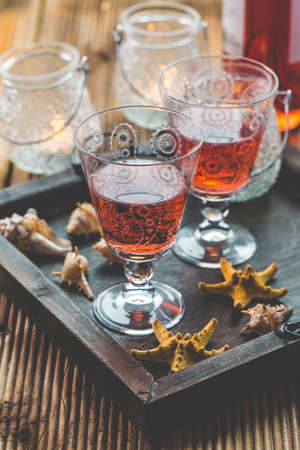 Two vintage glasses of red wine with bottle and lantern on wooden backgroundの写真素材