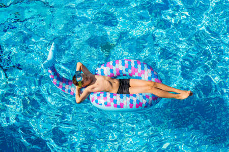 Boy relaxing on air mattress in the swimming pool - top viewの写真素材