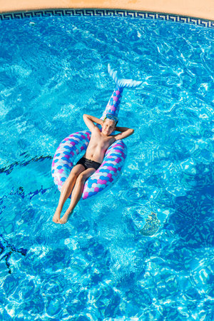 Boy relaxing on air mattress in the swimming pool - top view