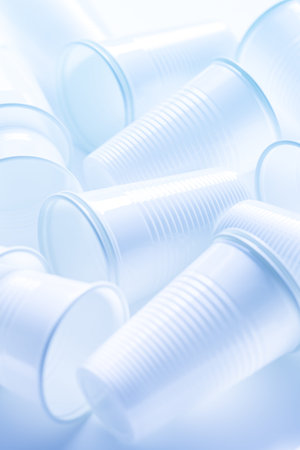 Disposable white plastic cups as background. Environmental concept. Non-compostable waste. In blue...