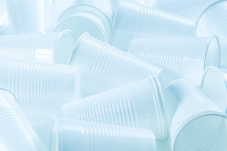 Disposable white plastic cups as background. Environmental concept. Non-compostable waste. In blue...