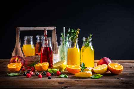 Assortment of juices and lemonades with fruits and herbs on wooden tableの写真素材