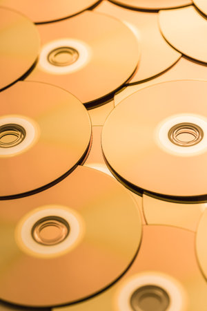 CDs and DVDs in golden tone as background. Soft focus.