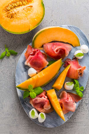 Traditional Italian appetizer - Prosciutto with cantaloup melon, mozzarella, basil and mintの写真素材