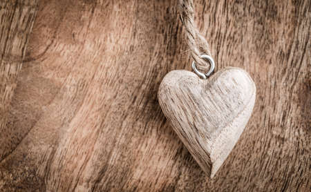 Small wooden heart on wooden background in vintage style. Symbol of love.の写真素材