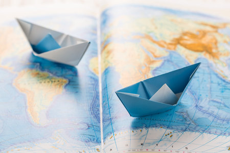 Small paper boats on world map. Concept of traveling or military exercise.