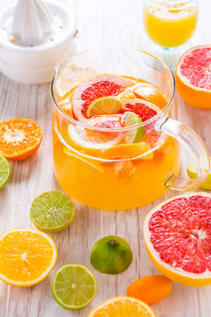 Freshly prepared ice tea or lemonade with assorted citrus fruits on wooden background.の写真素材