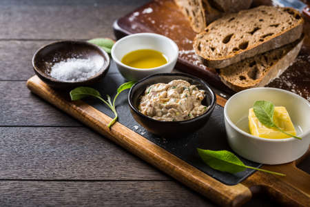 Tuna spread with fresh bread slice, sage butter, olive oil and salt on rustic wooden tableの写真素材